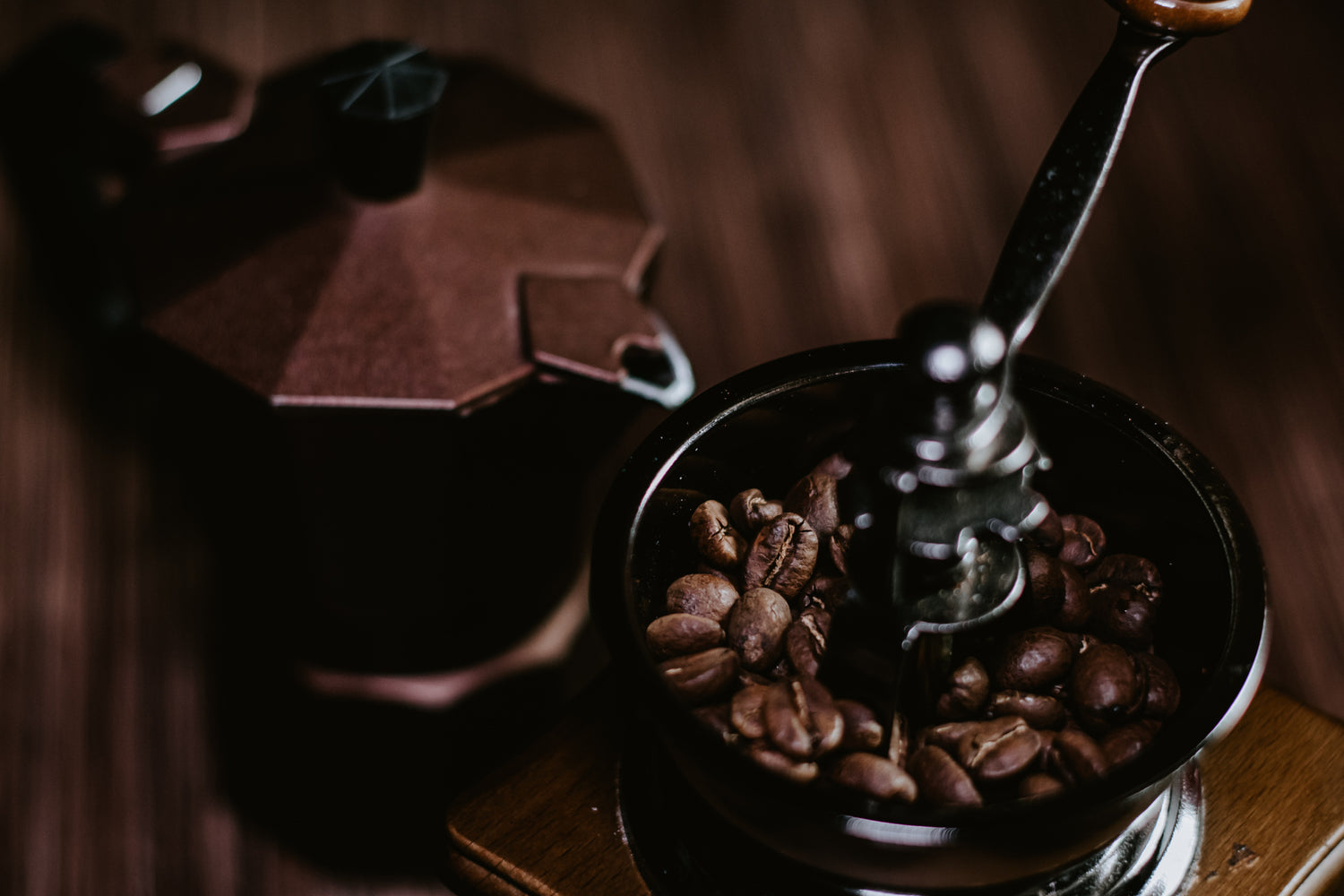 Top view of a small manual coffee grinder filled with coffee beans