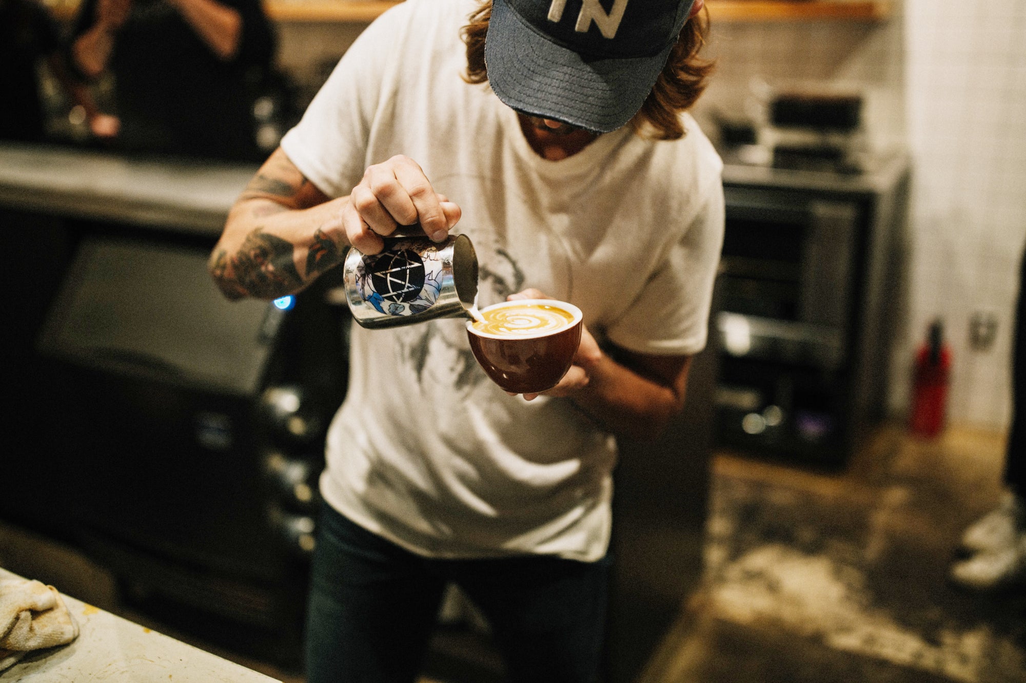 A barista carefully completing a latte pattern