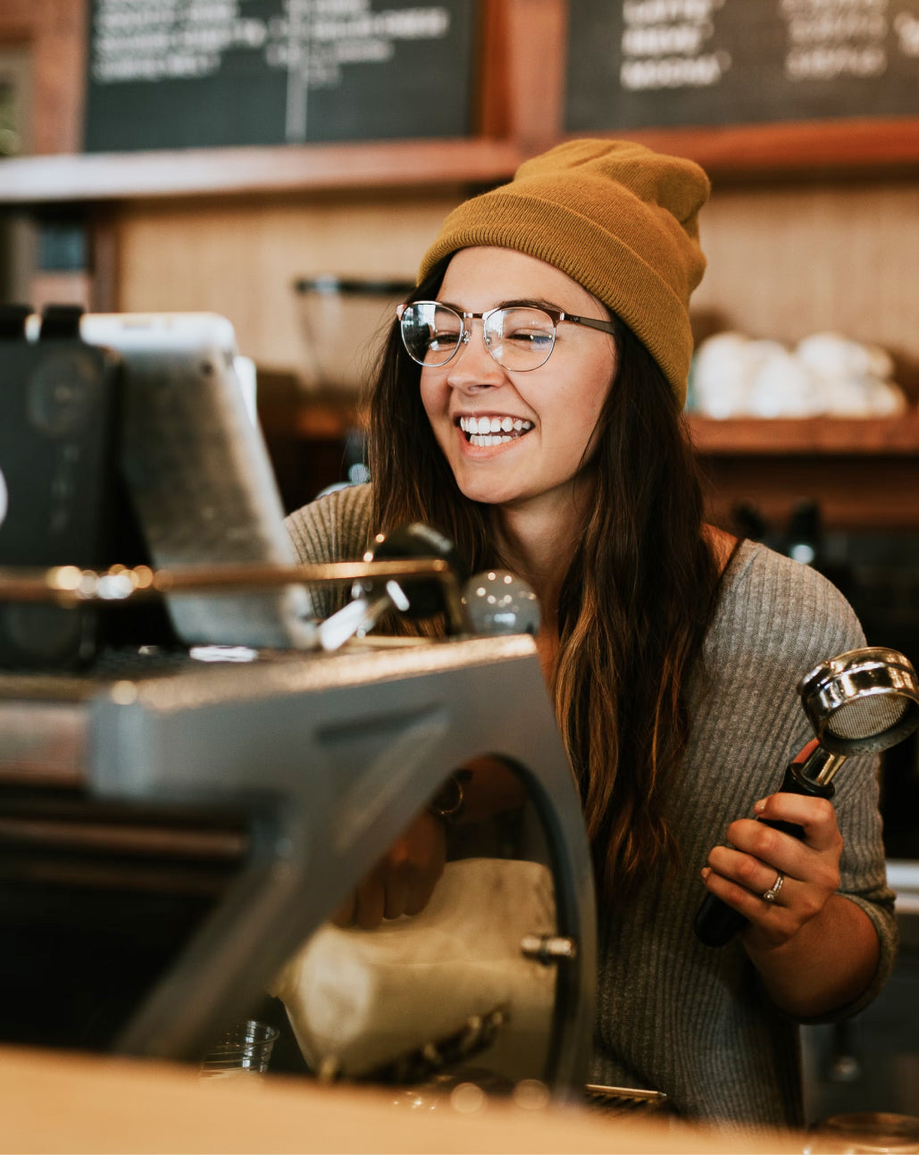 A woman barista at work, wearing a brown beanie