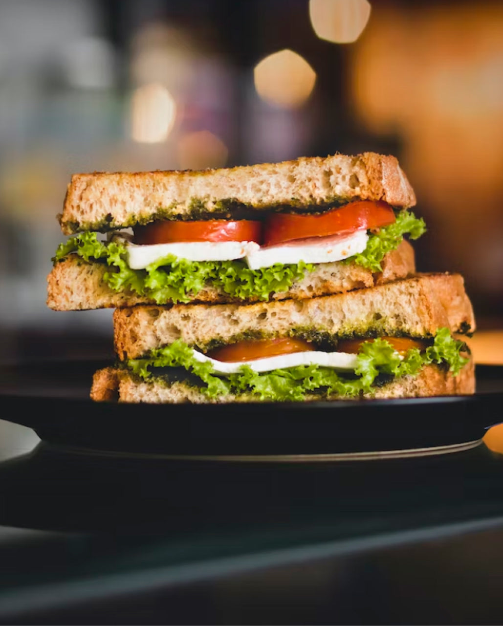 A sandwich cut in half featuring tomatoes, cheese, and lettuce.