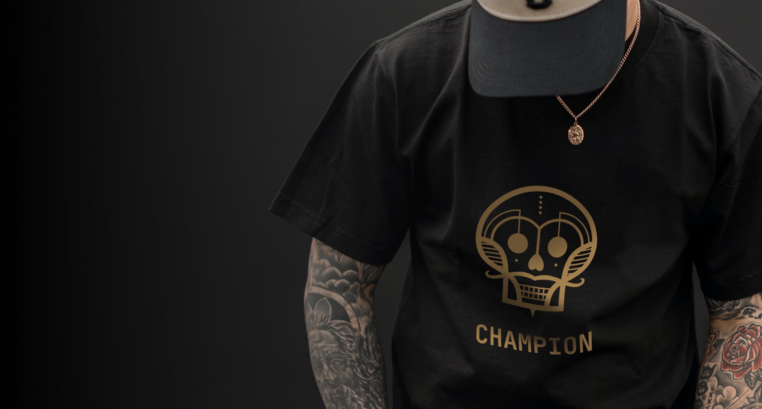 A tattooed man wearing a black t-shirt with the Champion logo