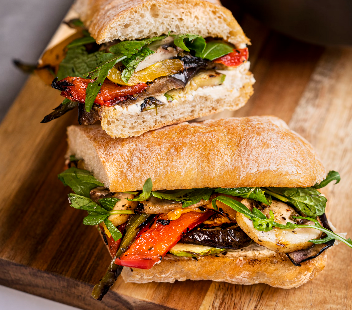 A sandwich featuring grilled vegetables and mint leaves