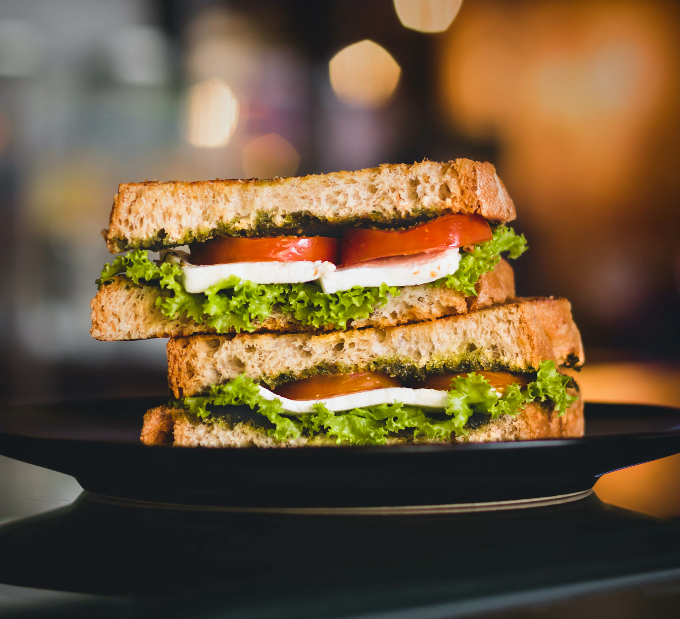 A sandwich cut in half featuring tomatoes, lettuce, and cheese